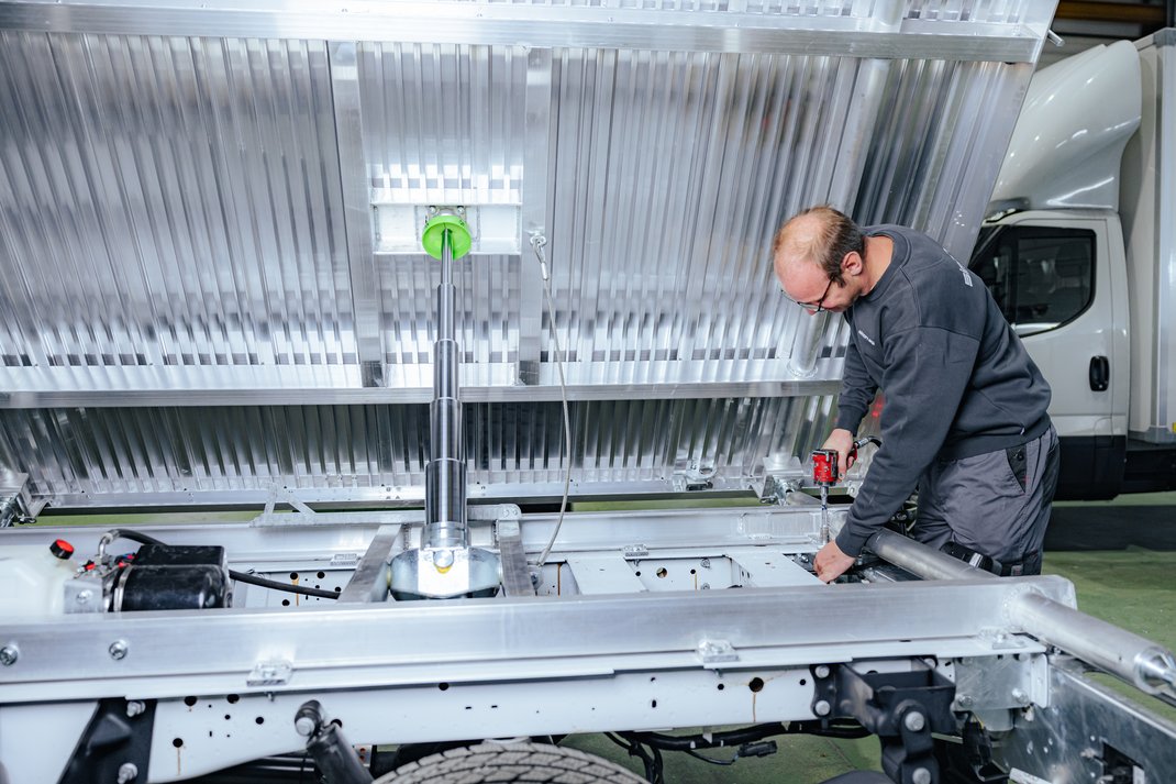 Ein Mitarbeiter von Simon AG arbeitet am Umbau eines Kipplasters